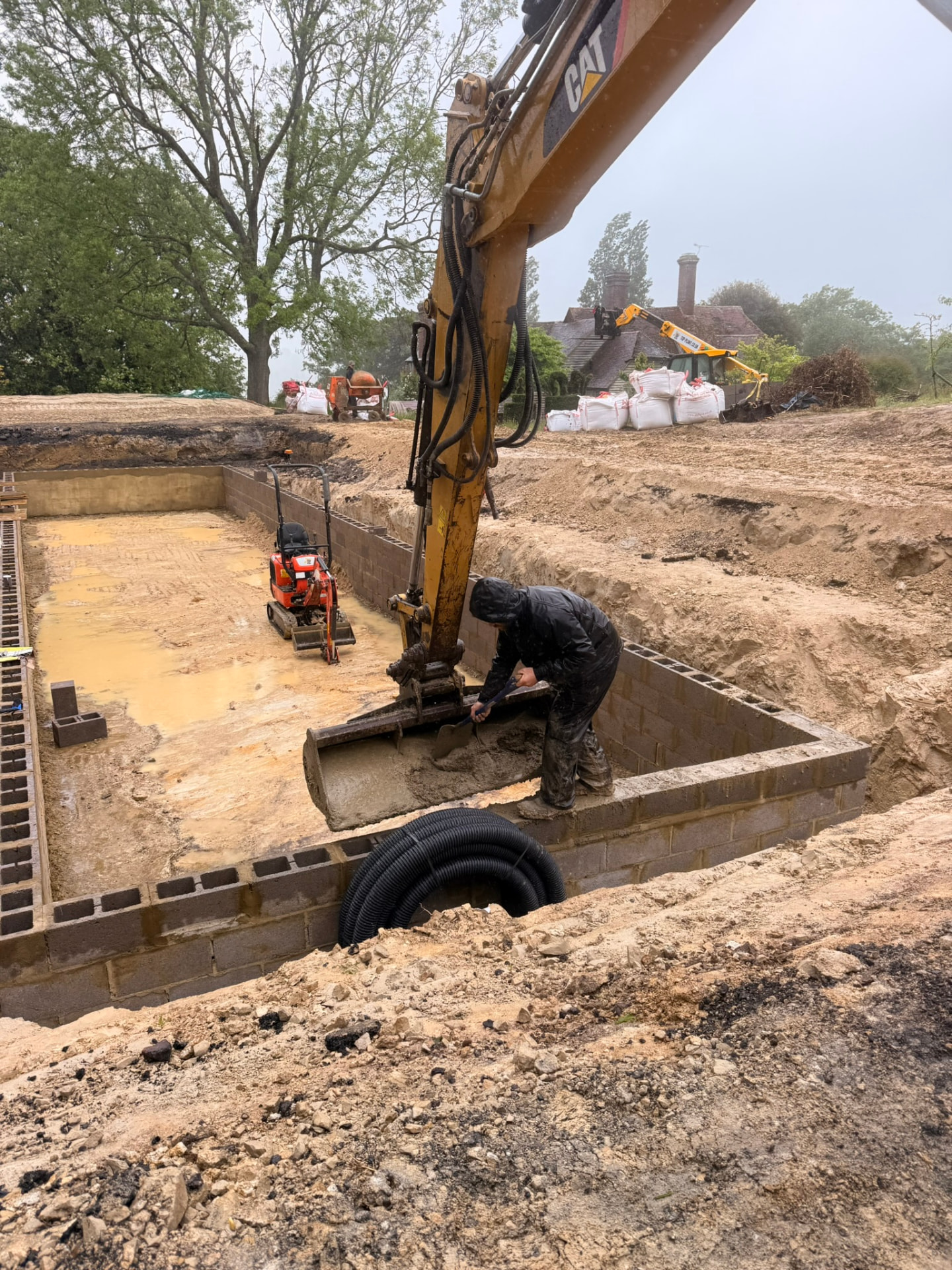 Extensive hard landscaping groundworks in a garden excavation, with a wall of concrete blocks being built