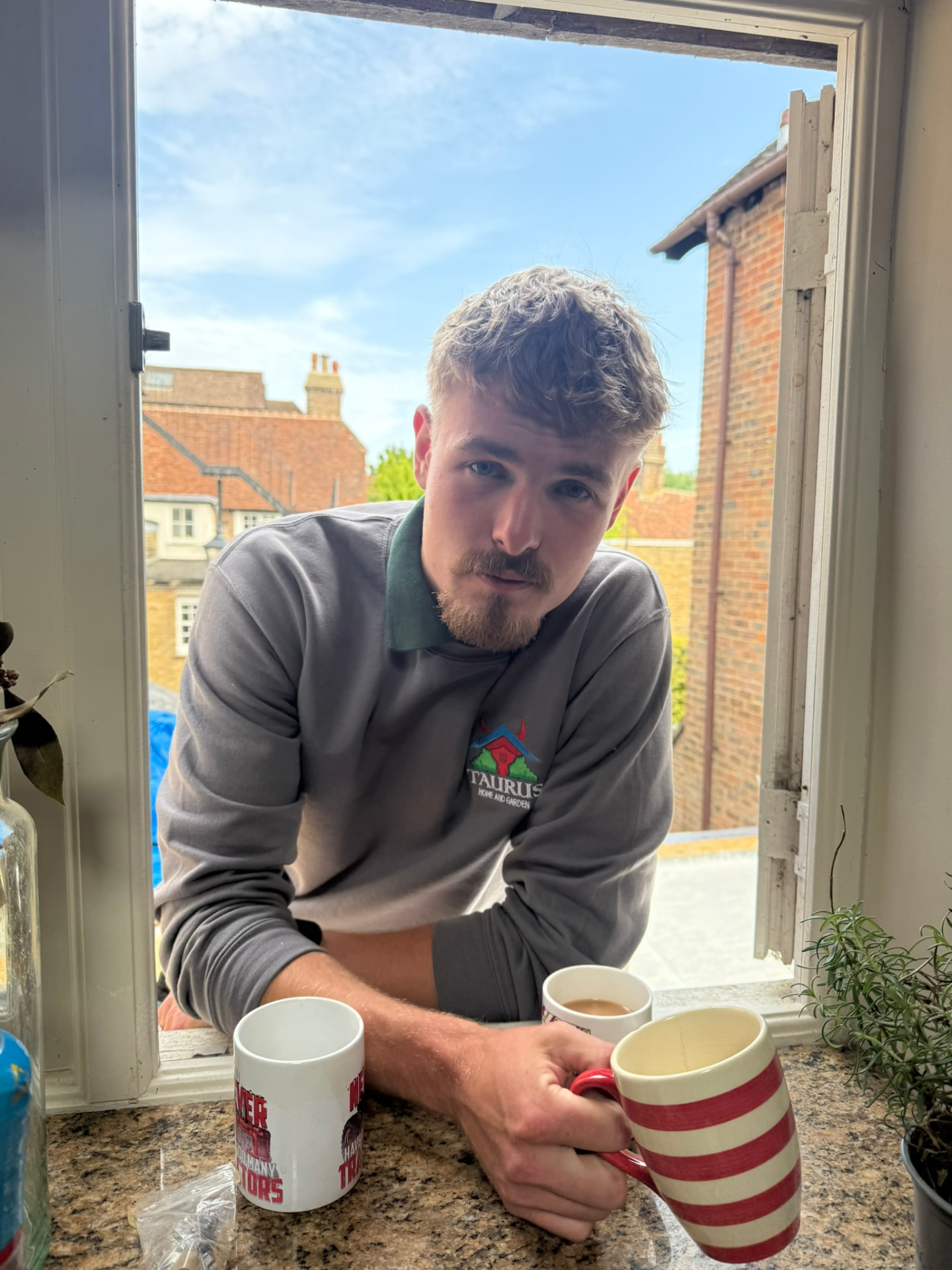 Freddie, founder of Taurus Home and Garden, leaning in through a window wearing a Taurus sweatshirt